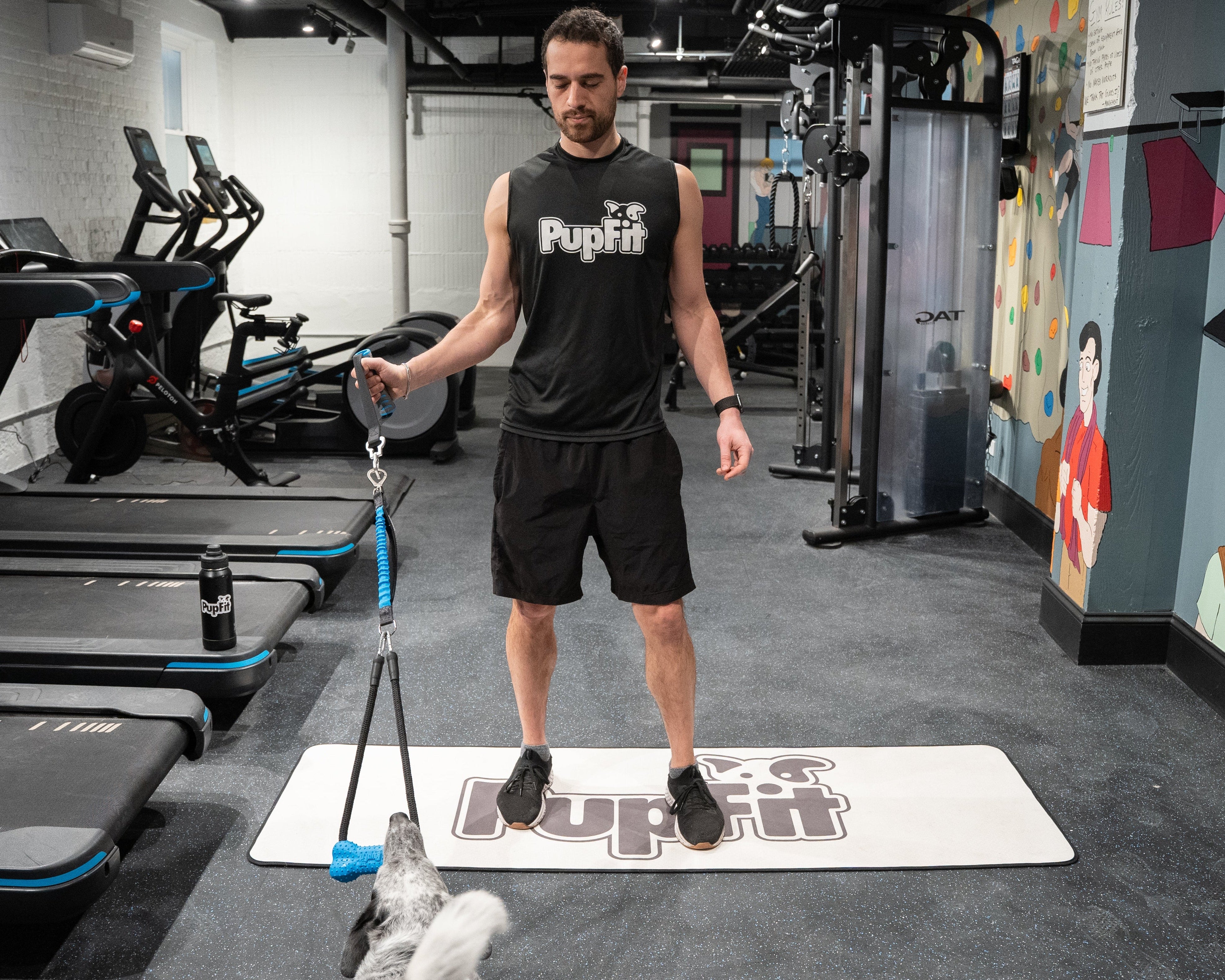 Man exercising with pupfit resistance tug toy in a gym setting