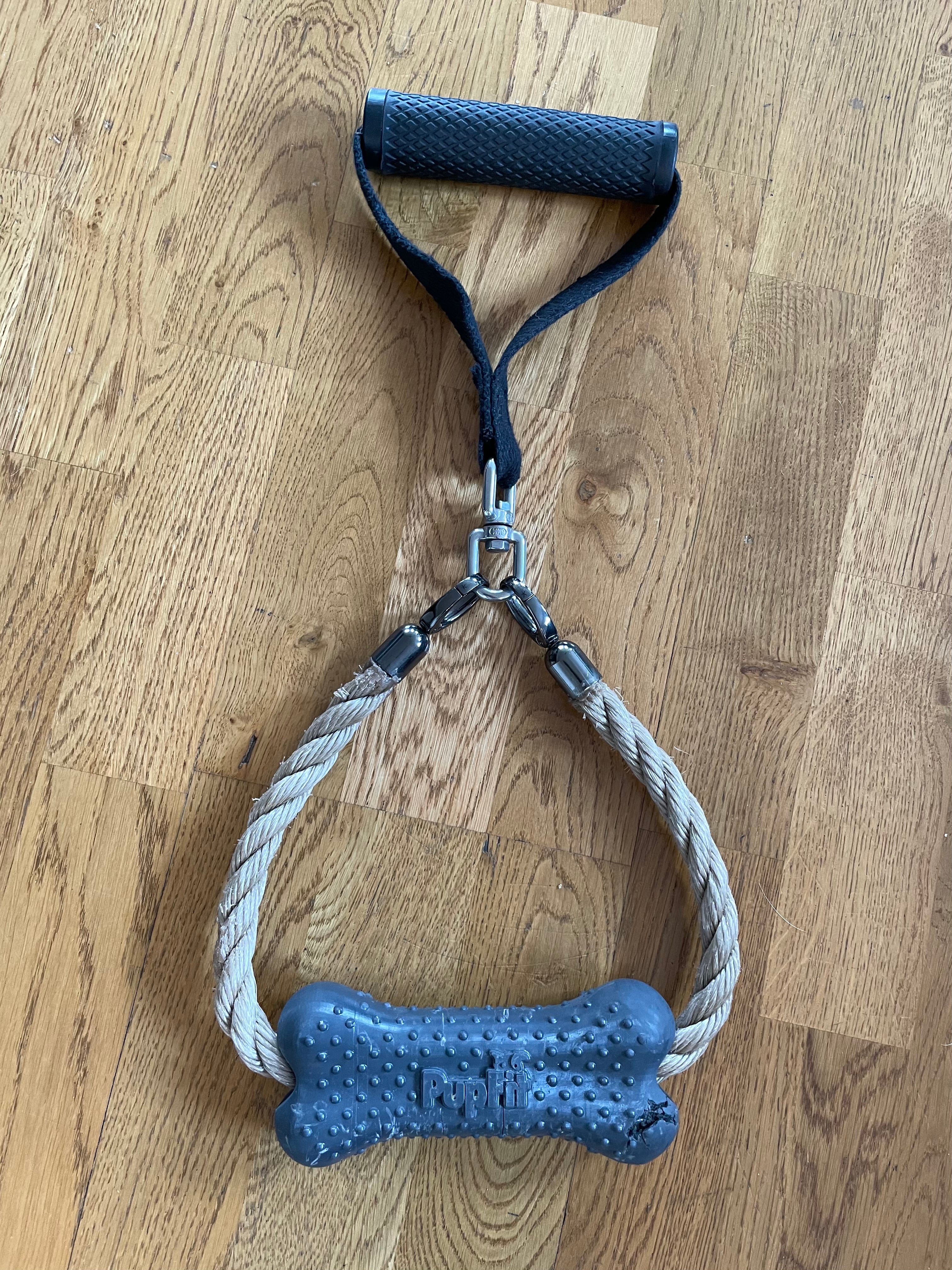 Gray dog chew toy prototype with a handle on a wooden floor