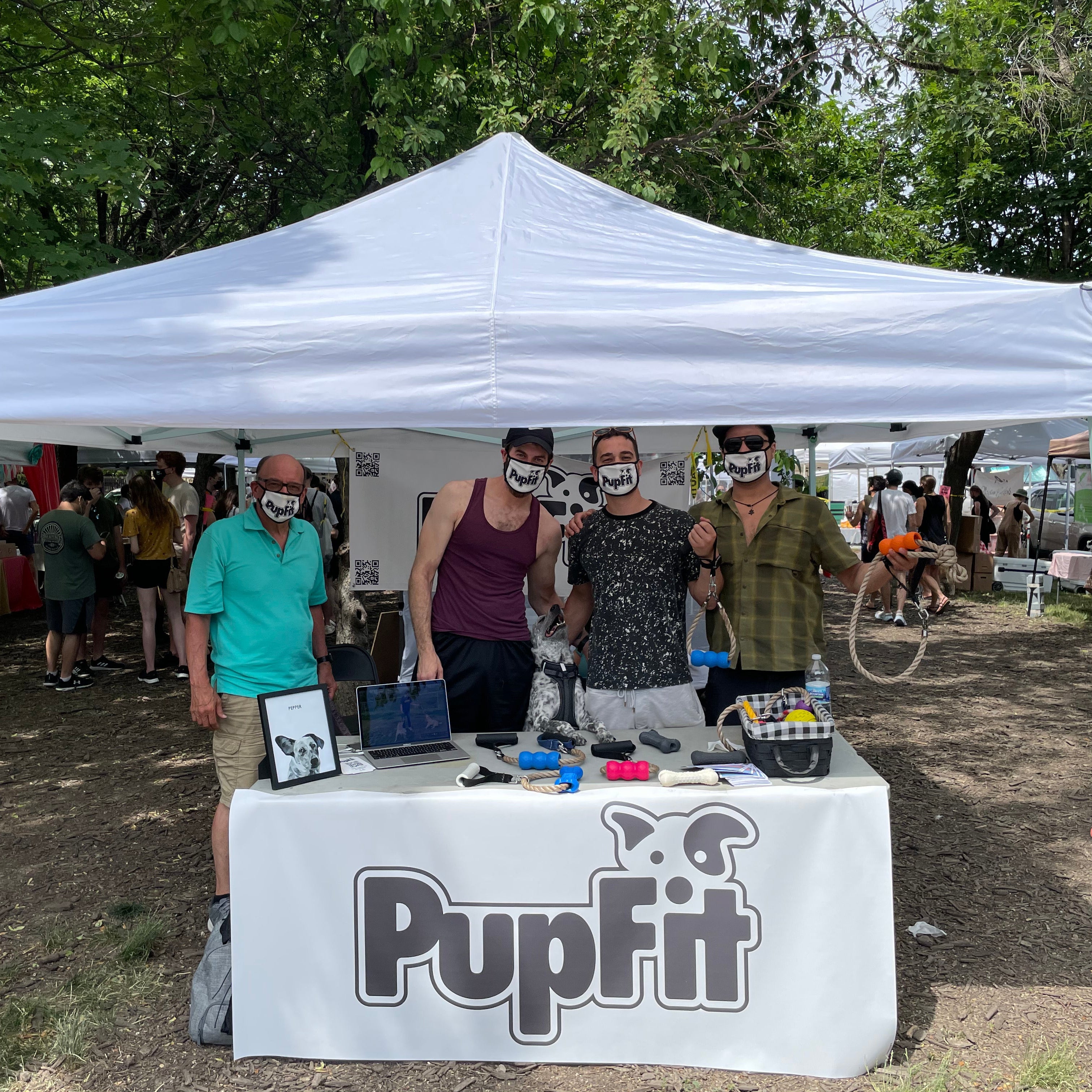 Group of people standing behind a 'PupFit' booth at an outdoor event.