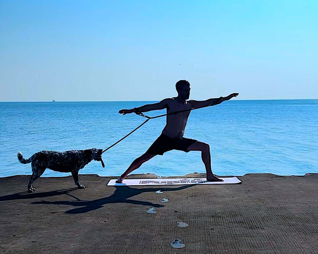 Dog owner doing yoga with PupFit tug toy at the lake — outdoor human-dog workout