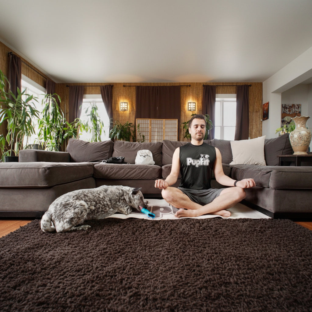 Man meditating on a rug with a dog enjoying a treat inside a pupfit pupbone beside him in a living room.